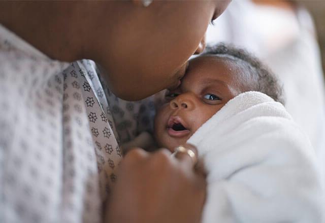 mother in hospital gown holds baby