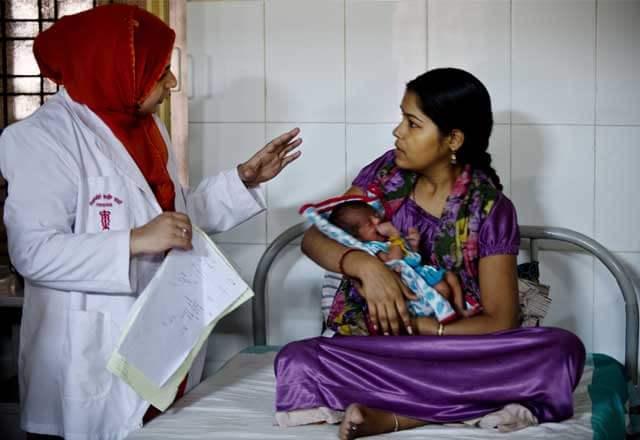 doctor speaks to patient holding baby