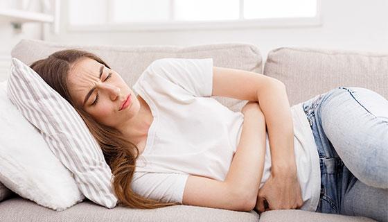 woman clutching stomach on sofa