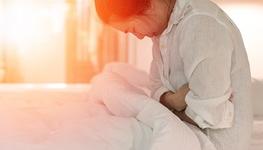 woman holding stomach in bed