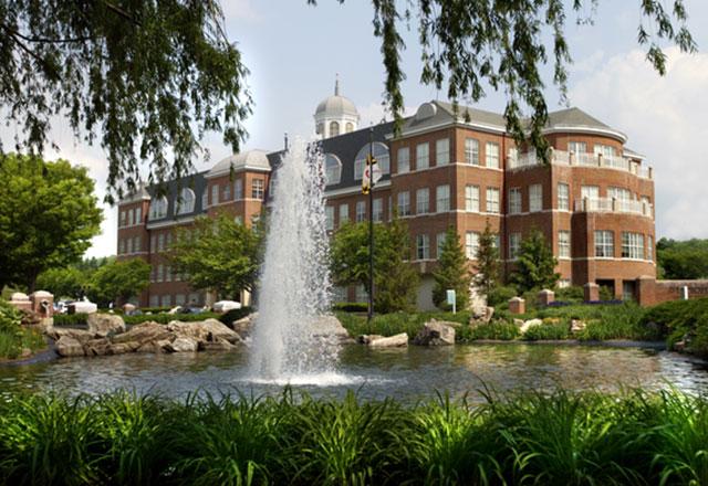 A fountain burbles in the foreground amongst lush landscaping, with Pavilion I at Green Spring Station visible behind it.