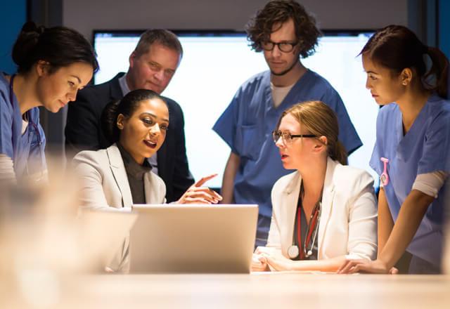 a group of doctors gathering around a computer