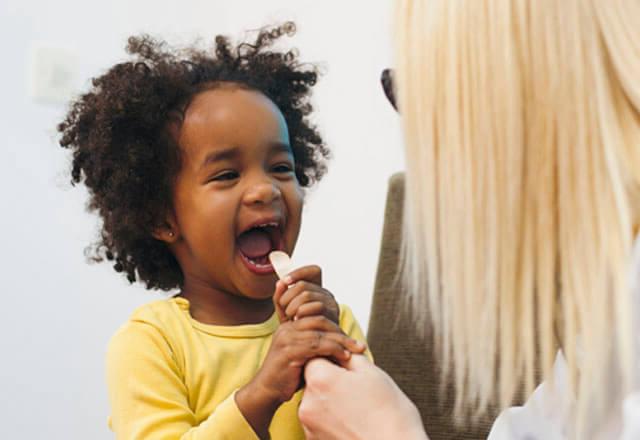 doctor with pediatric patient holding tongue depressor