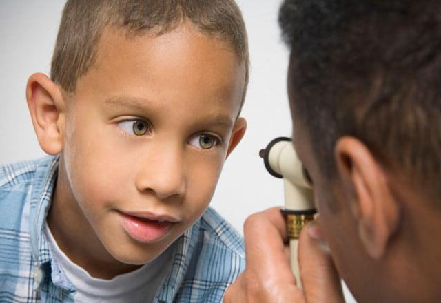 A young boy has his eyes checked by a doctor